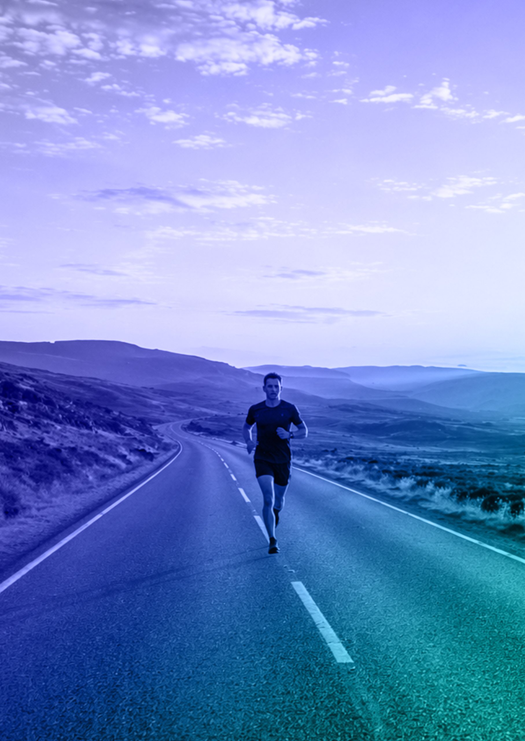 Runner on an open road surrounded by a mountainous landscape