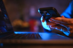 a man holding his phone using his laptop